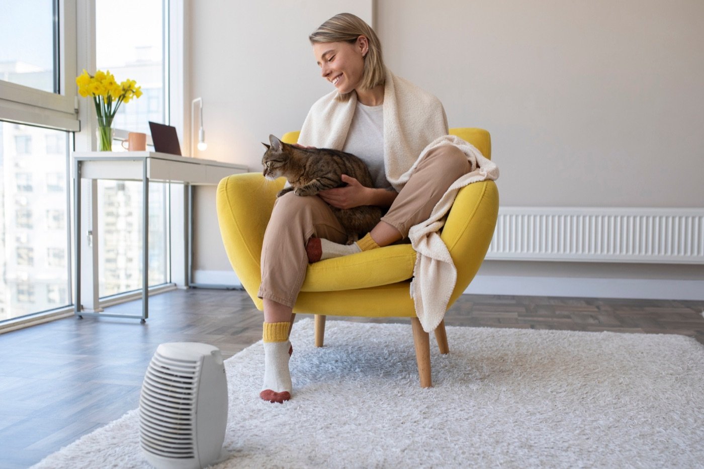 Frau in einem warmen Wohnzimmer mit einem mobilen Heizgerät